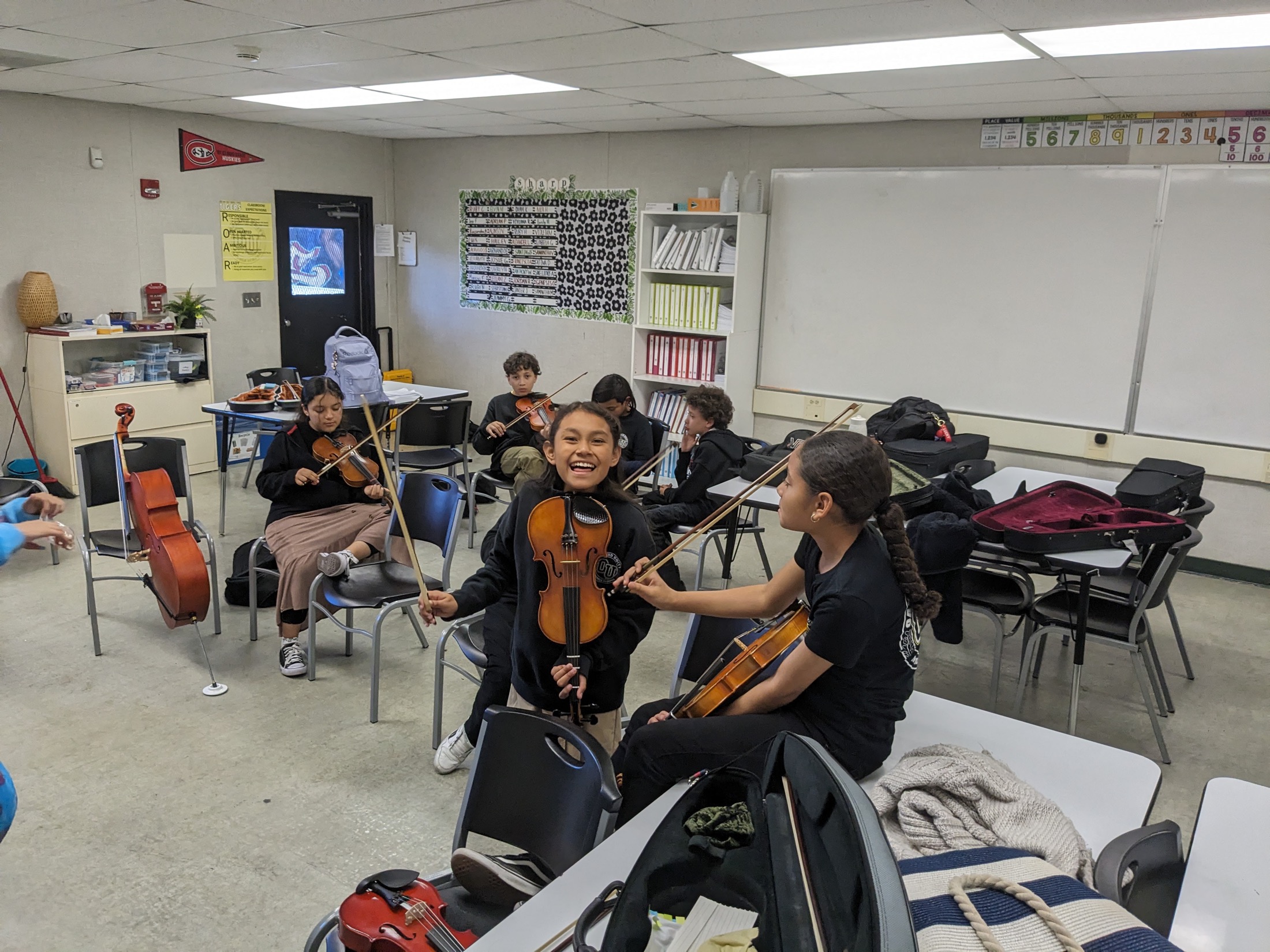 Oakland students playing violins together in class